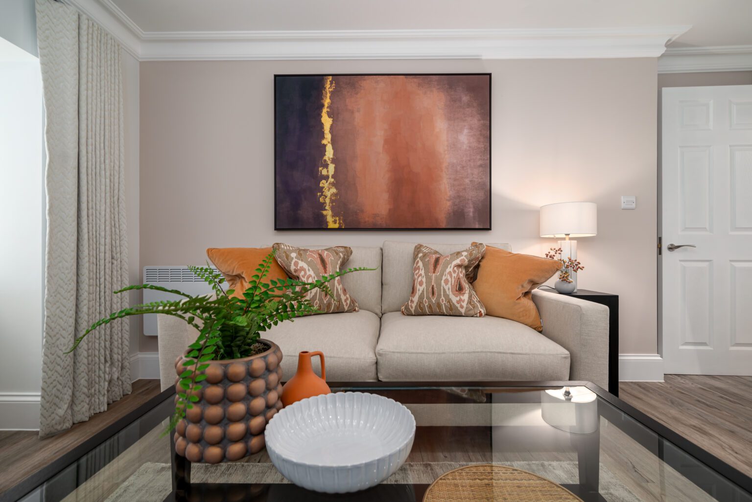 grey sofa living area with print behind on wall and potted plant on coffee table