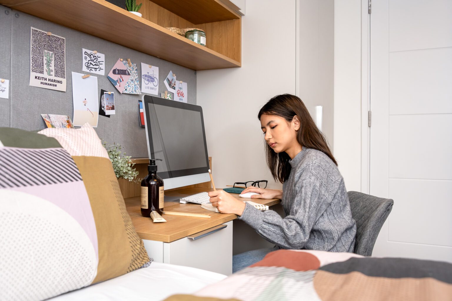 Student studying, sat at their desk with their computer in front of them.