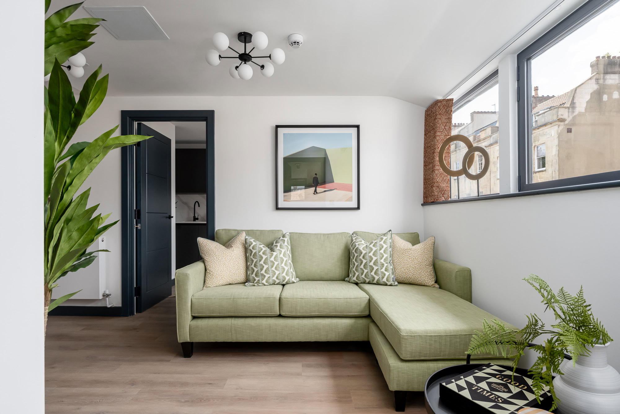 A living room with a green couch and a plant.