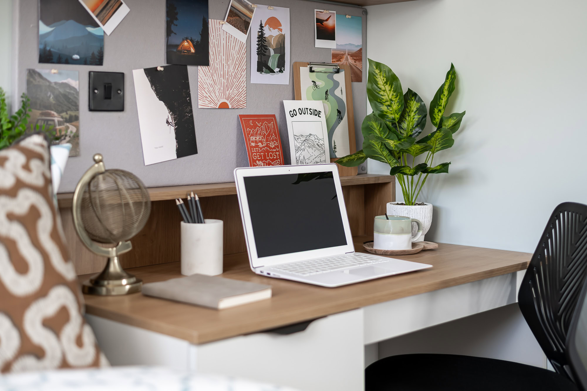 A laptop sits on a desk in a room.