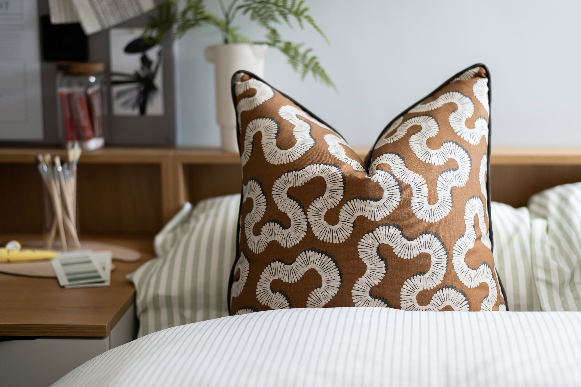 A pillow with a pattern on it sits on a bed.