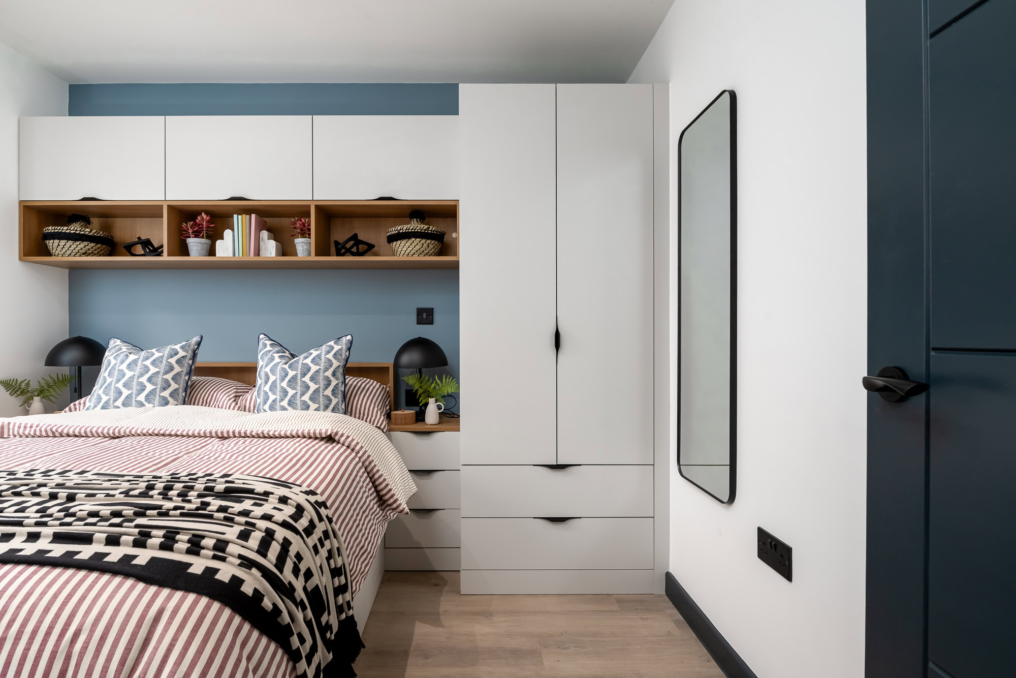 A bedroom with a bed, dresser and shelves.