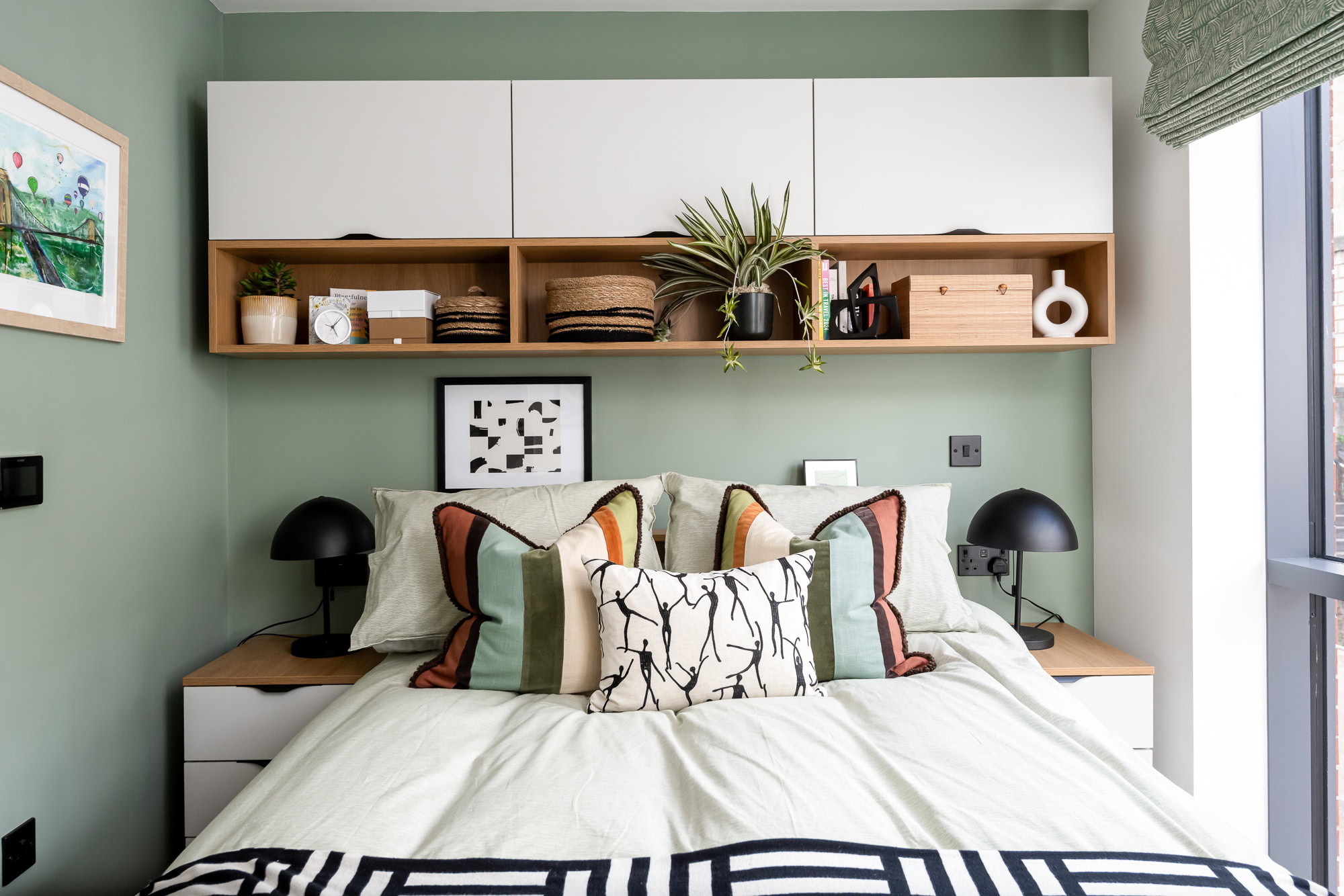 A bedroom with a bed, desk and a painting.
