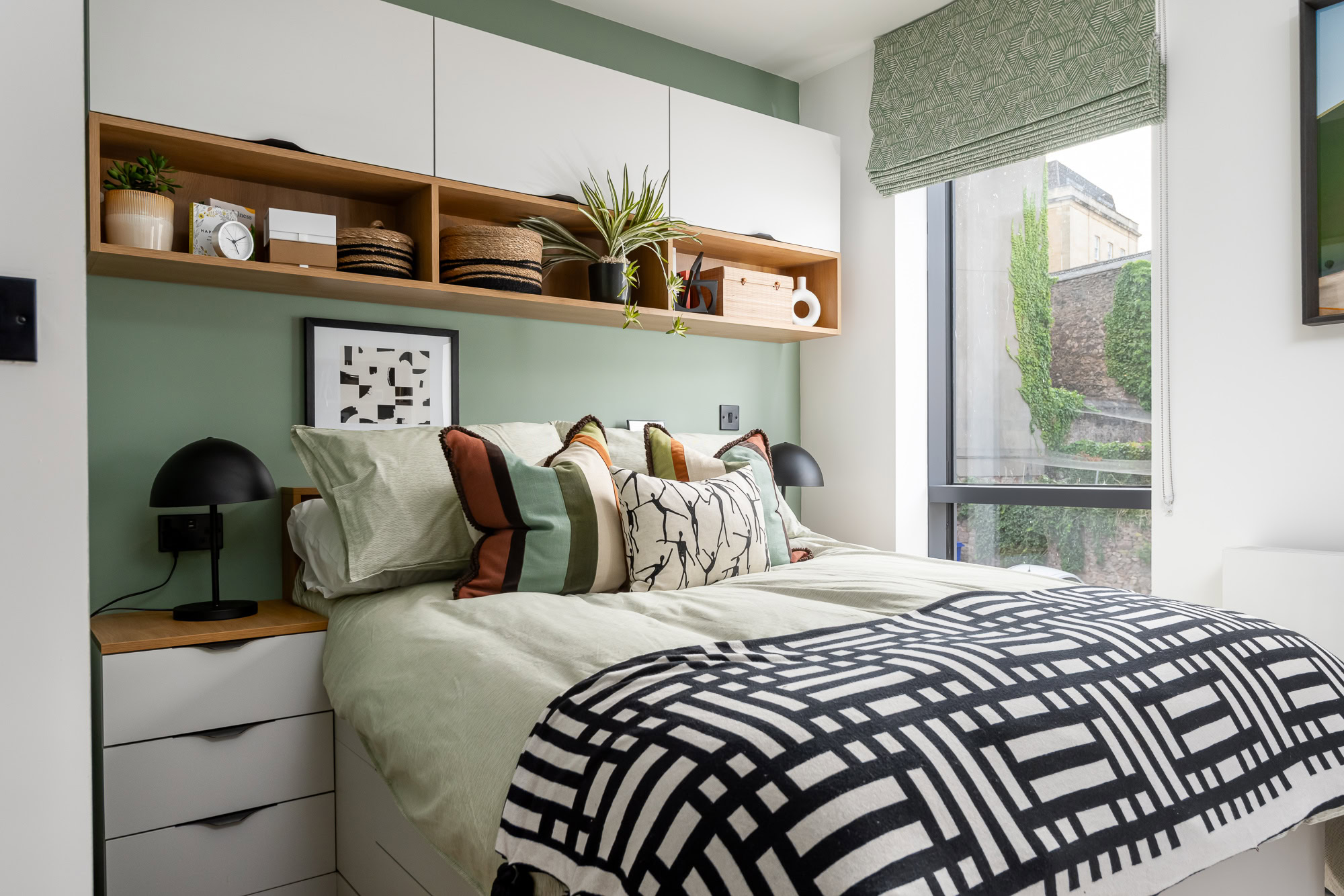 A bedroom with green walls and white furniture.
