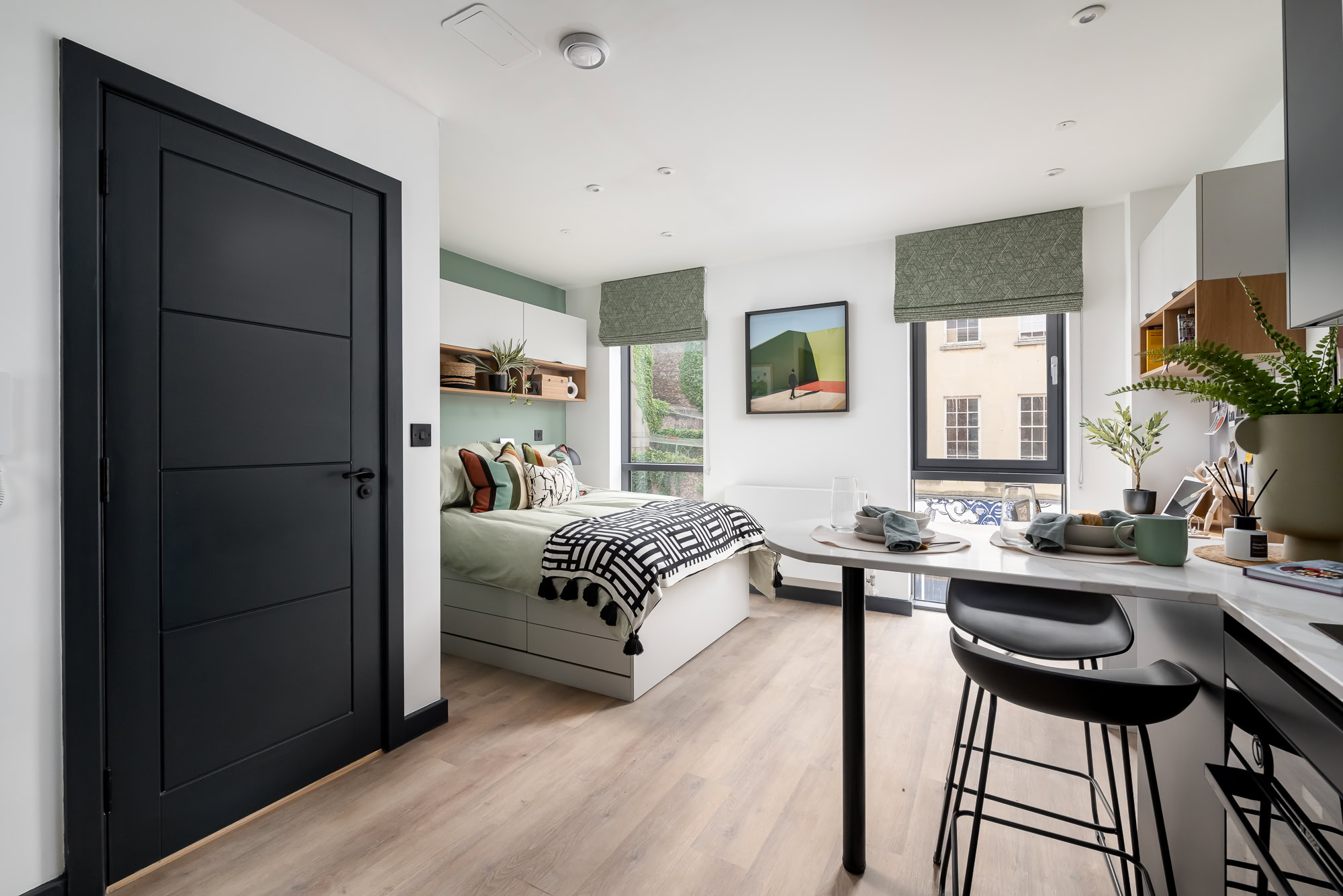 A small bedroom with a bed, desk and a window.