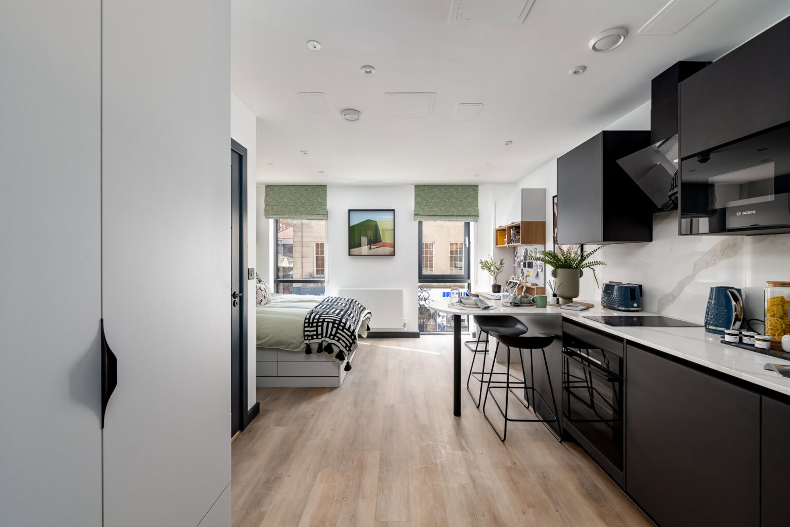 A small apartment with a bed, kitchen and a window.