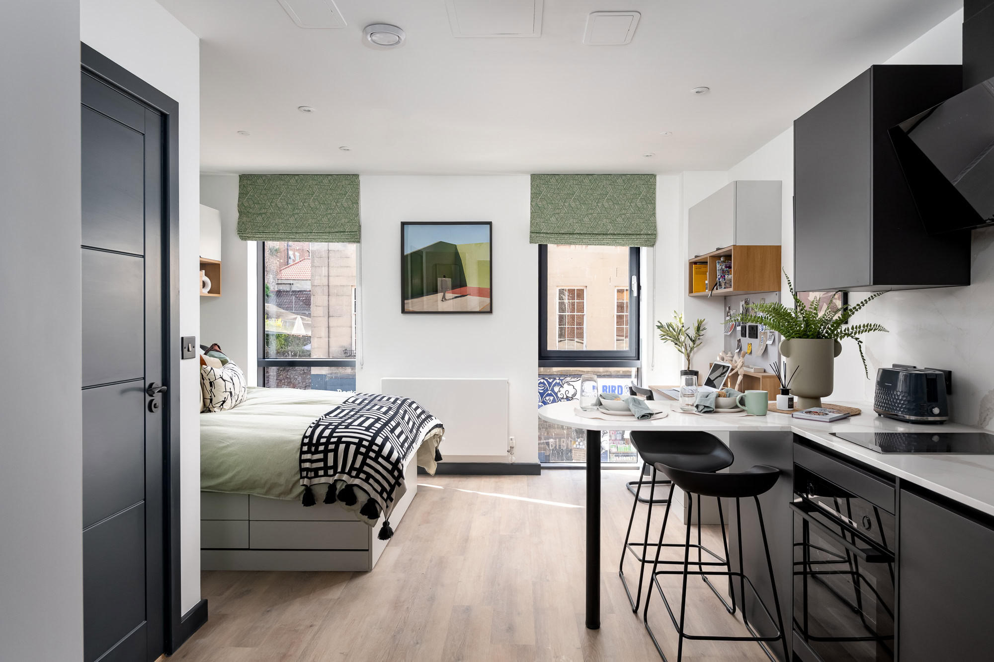 A small apartment with a bed, kitchen and a window.