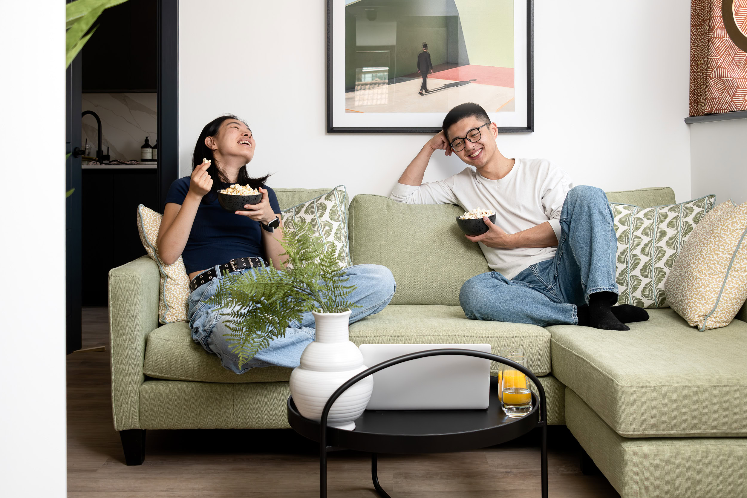 A couple sits comfortably on a couch, enjoying a bowl of popcorn during a cozy movie night.