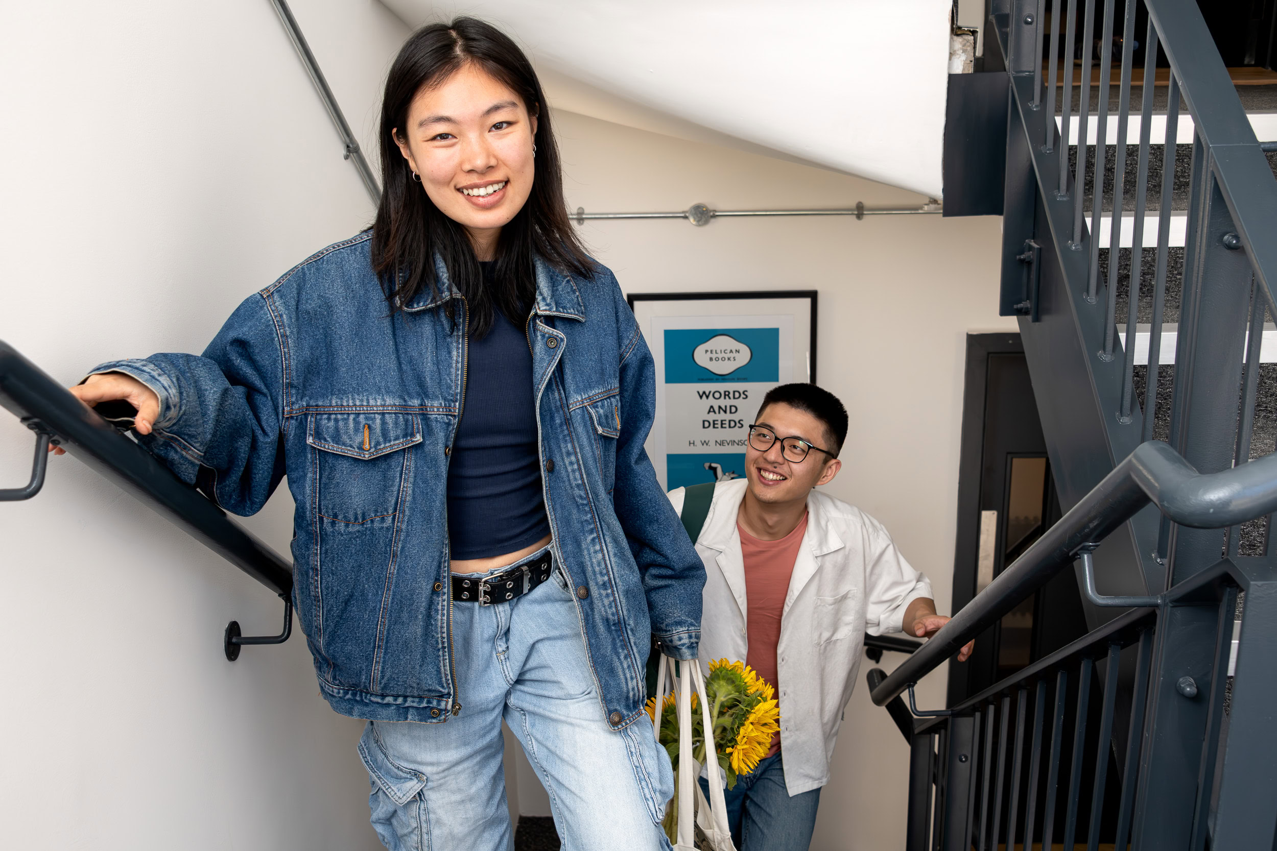 A young woman in jeans and a jacket stands confidently on a stairway, looking off to the side.