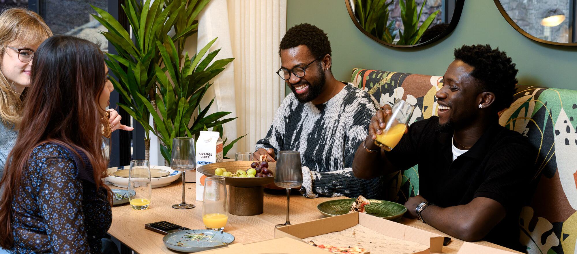 A group of people gathered around a table, enjoying slices of pizza together in a casual dining setting.