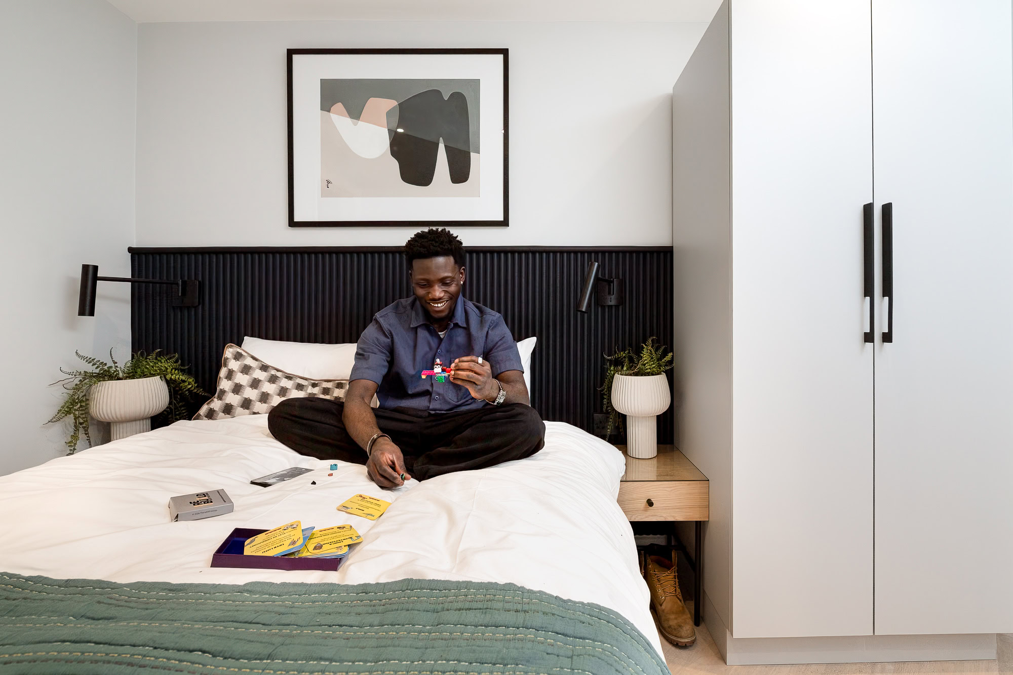 A man relaxed on a bed, holding a game controller while engaged in gaming.