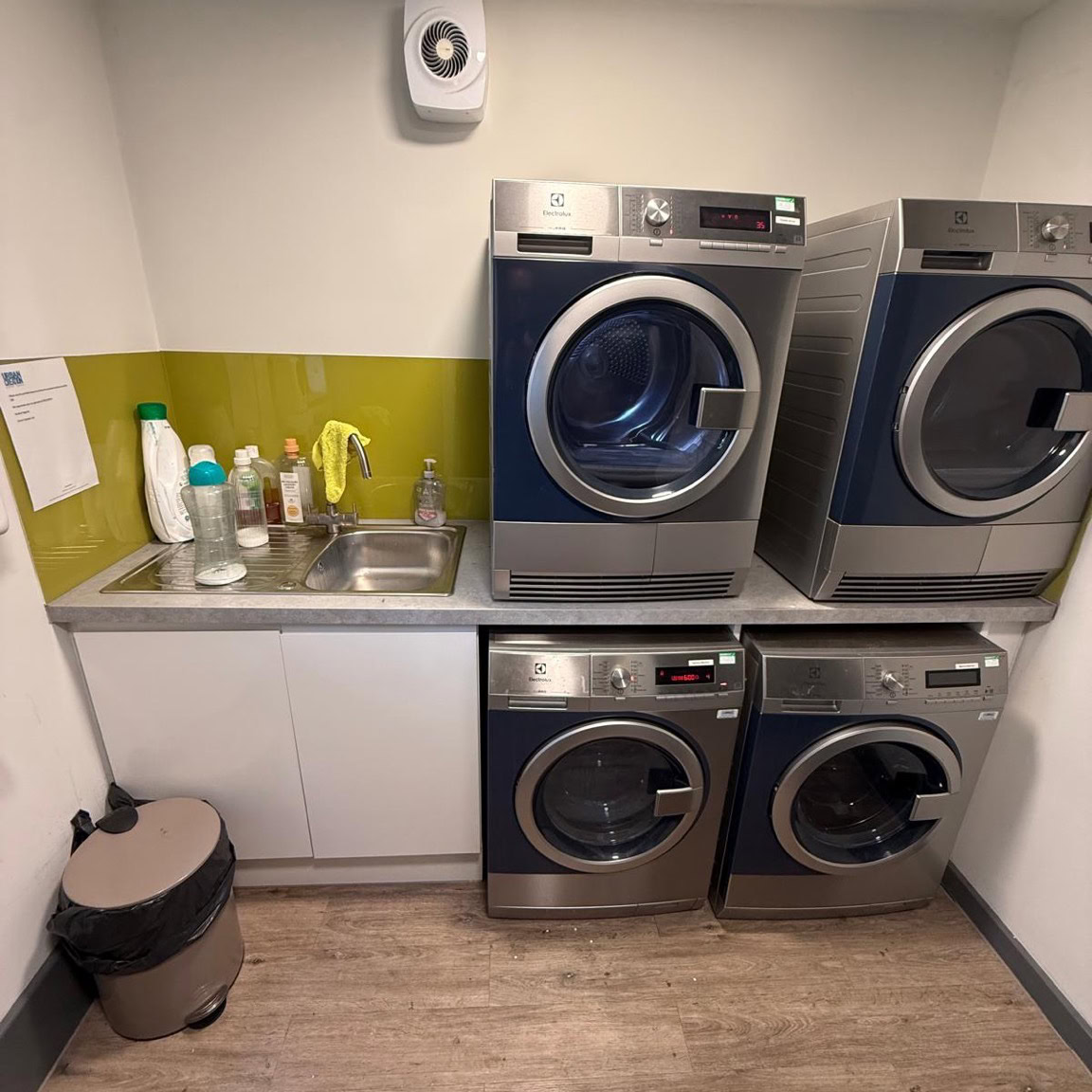 A communal laundry room in an Urban Student building in Bristol, with four Electrolux washing machines and dryers above a sink.