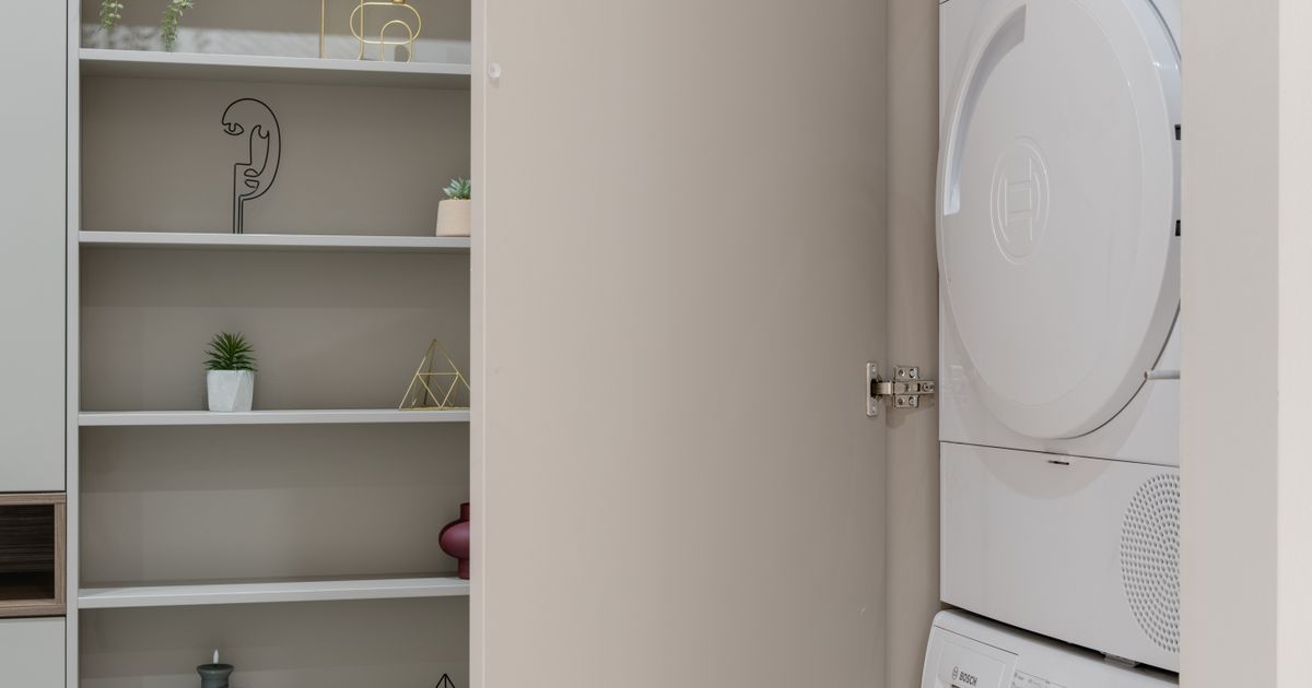 A washer and dryer neatly built into a modern laundry cupboard in a student apartment.