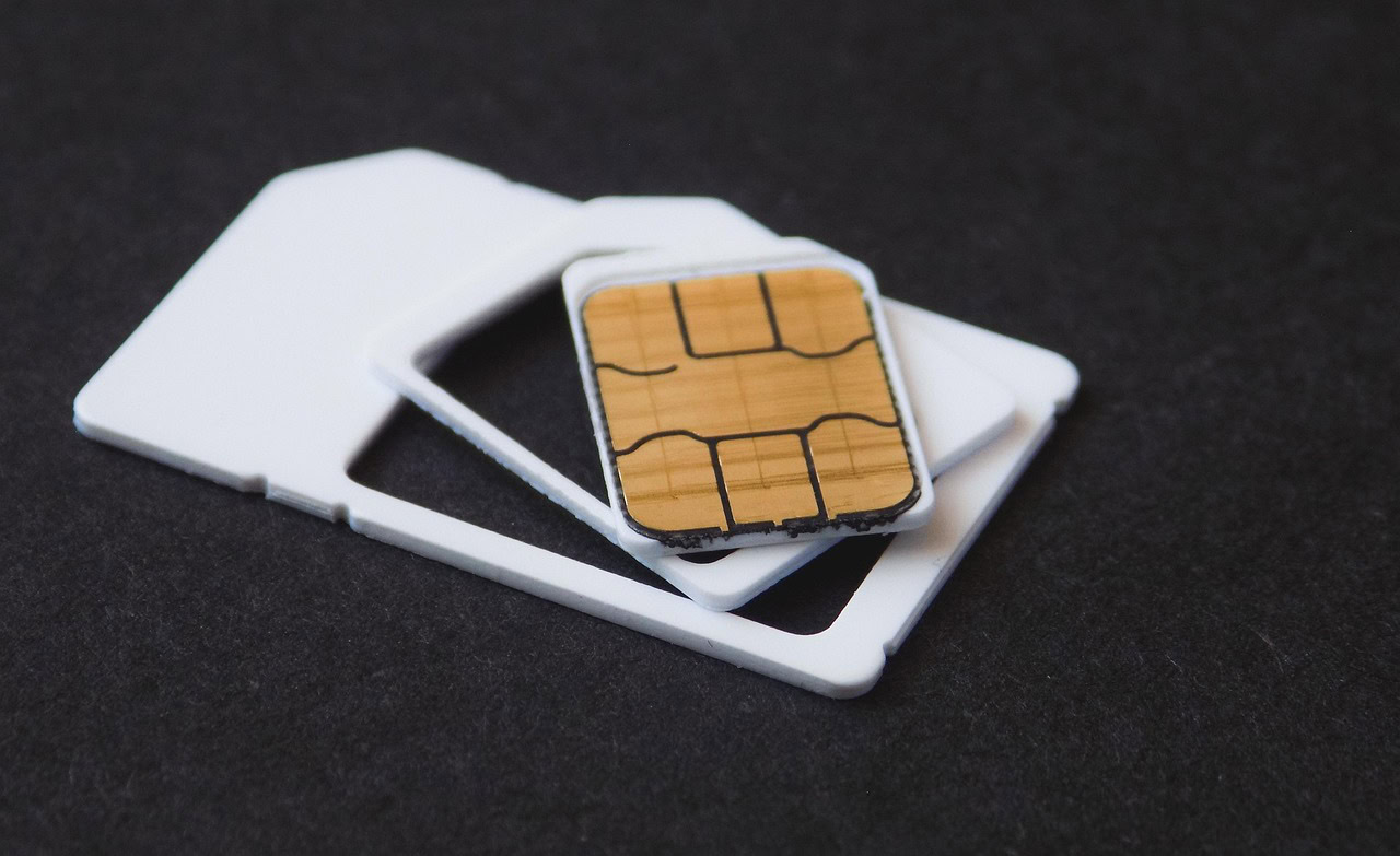 A UK SIM card resting beside a smartphone, ready to be fitted on arrival.